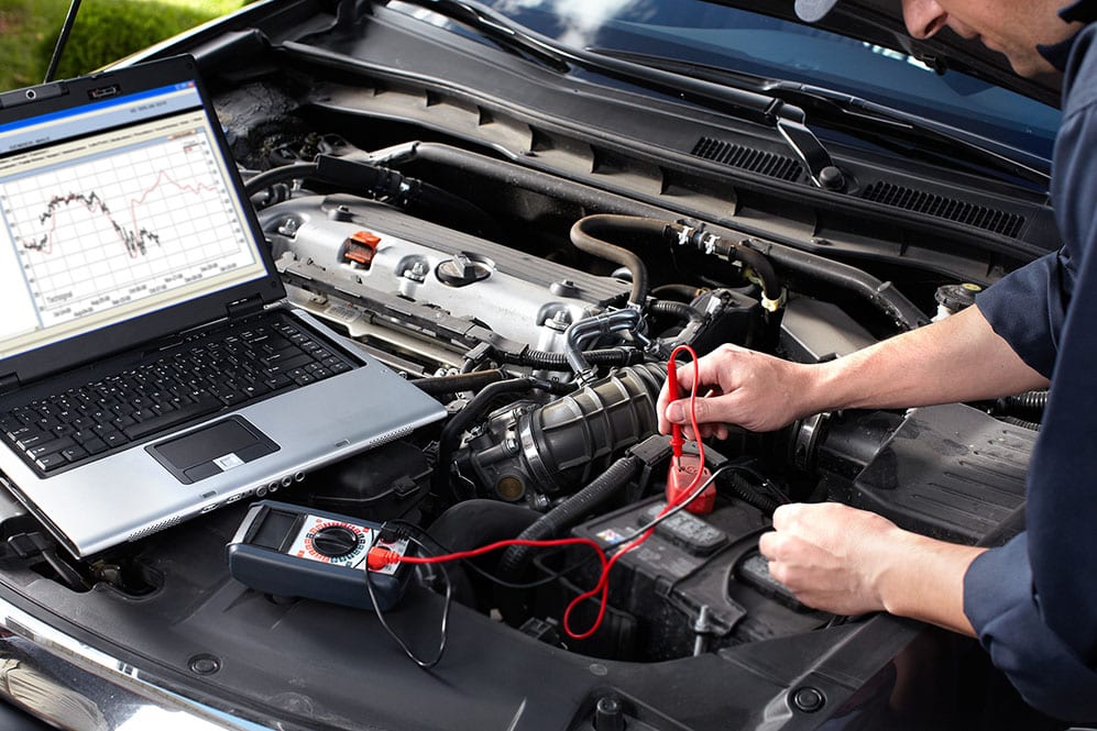 mechanic with laptop checking engine